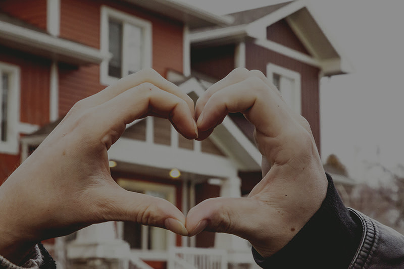 hands in heart shape in front of townhouse